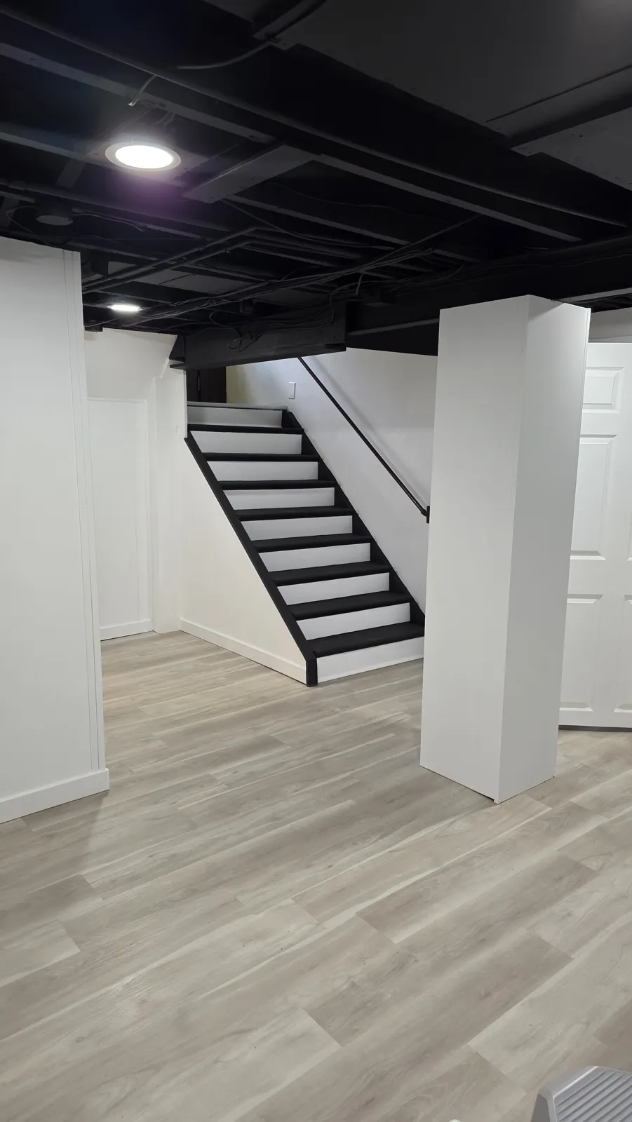 Finished basement with black ceiling and staircase