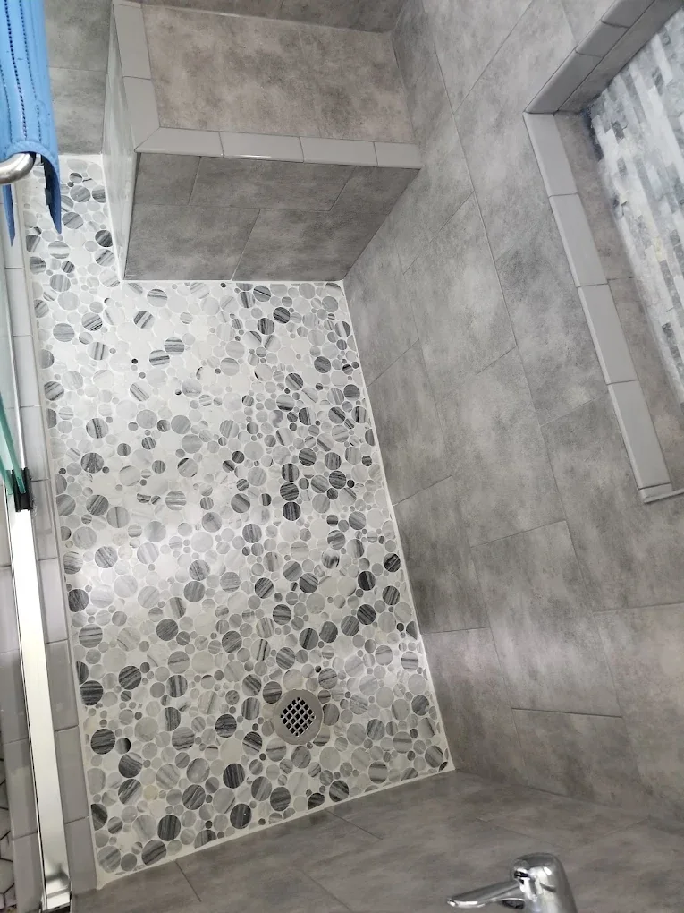 Walk-in shower with gray wall tile and pebble mosaic floor