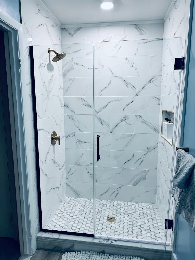 Glass shower with marble-look tile walls