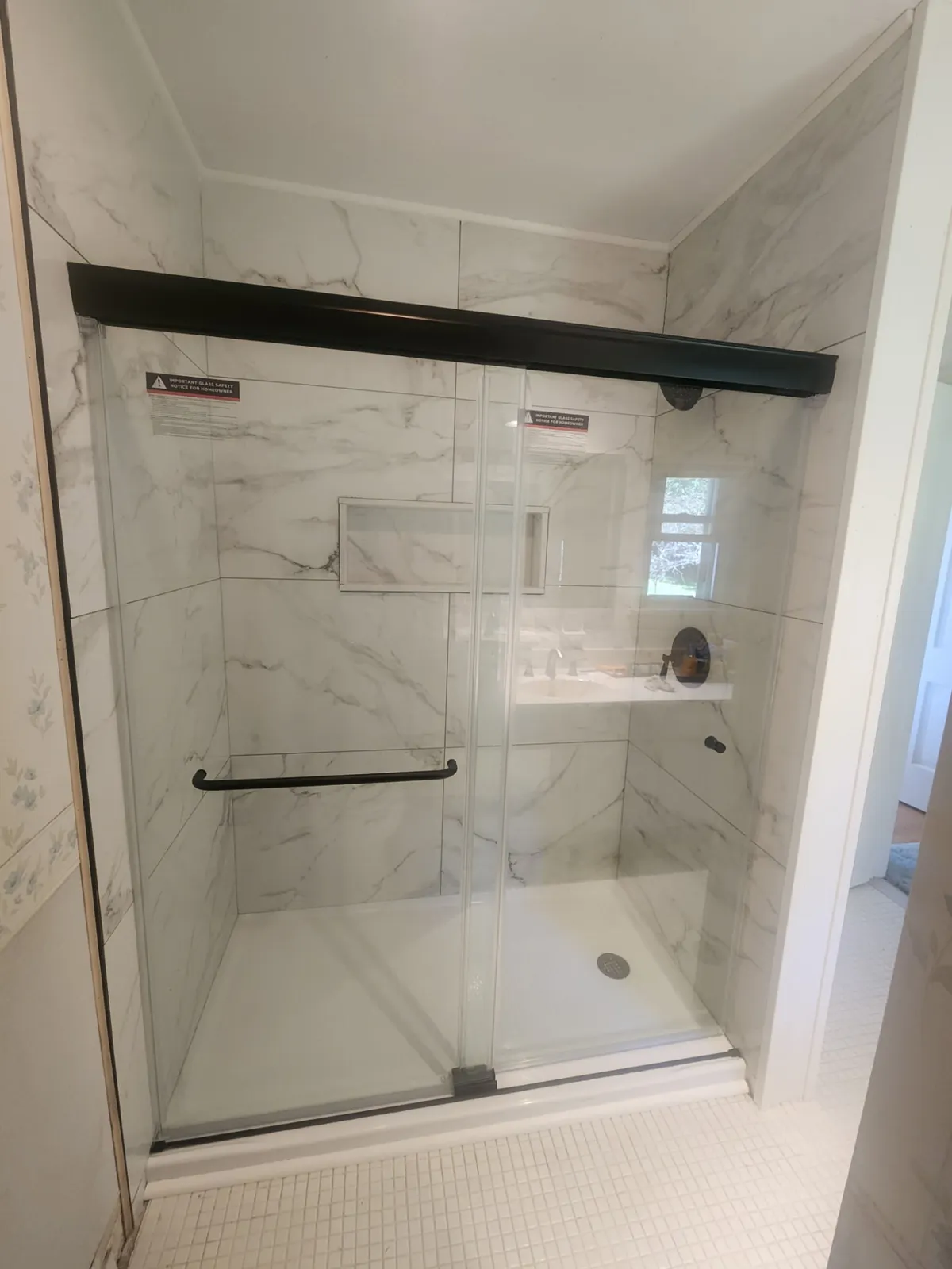 Glass shower with marble-look tile and black hardware