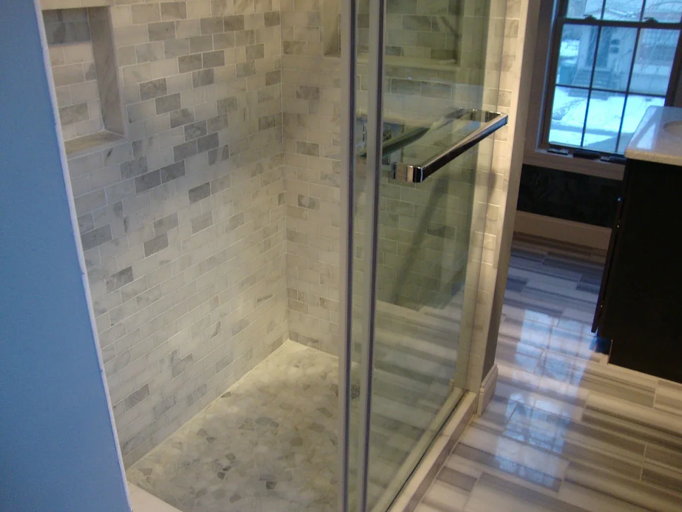 Walk-in shower with glass enclosure and stone-look tile