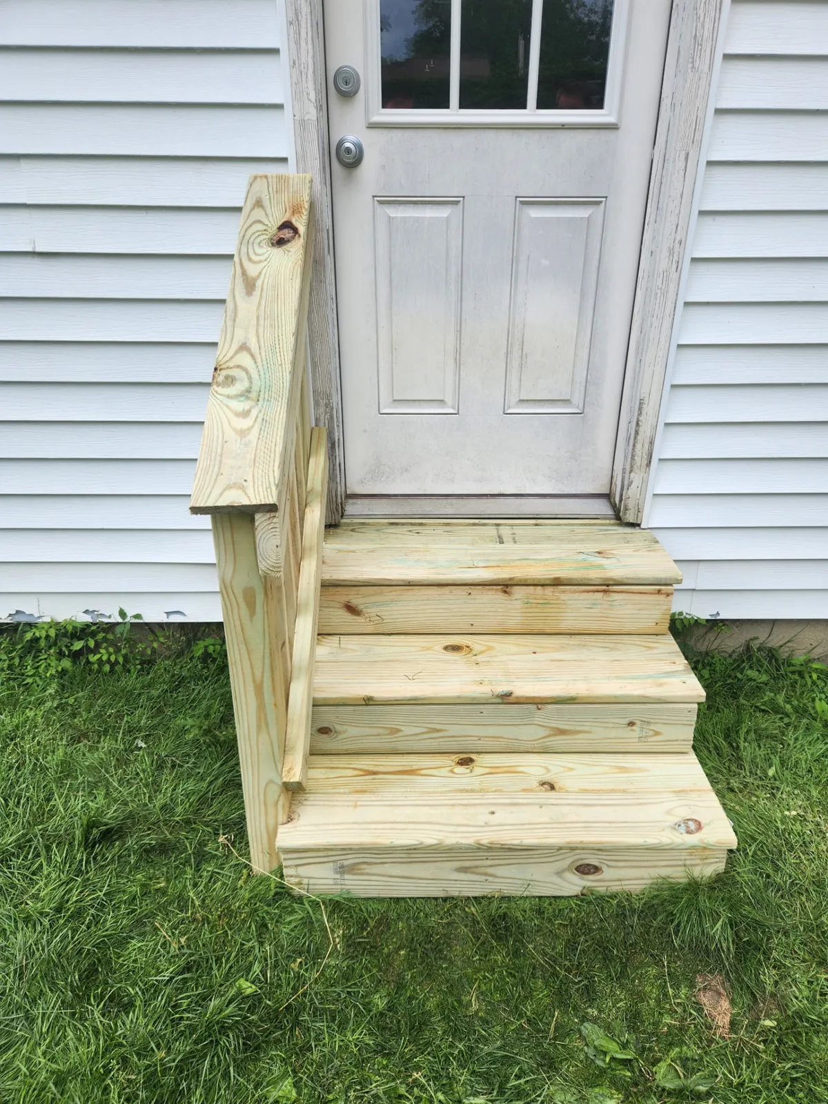 New pressure-treated wood steps with railing